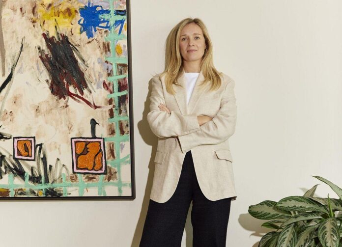 Retrato de Laura Fursdon, fundadora e CEO da Calder & Co, com um fundo de parede clara e planta verde ao seu lado.