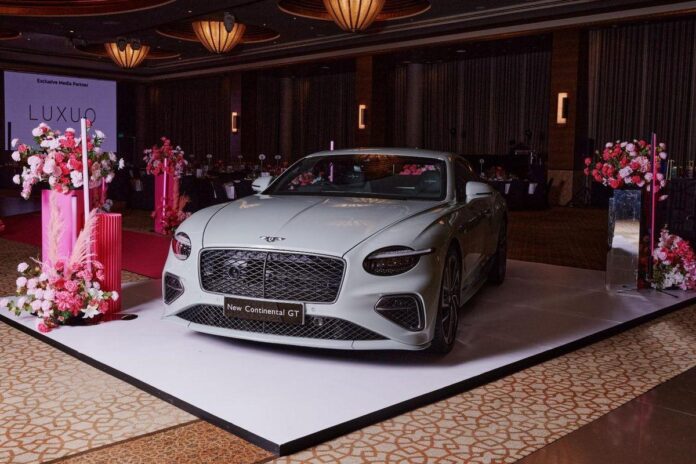 Um salão decorado para um evento, com mesas dispostas e iluminação suave, decorado com arranjos florais em tons de rosa e branco.