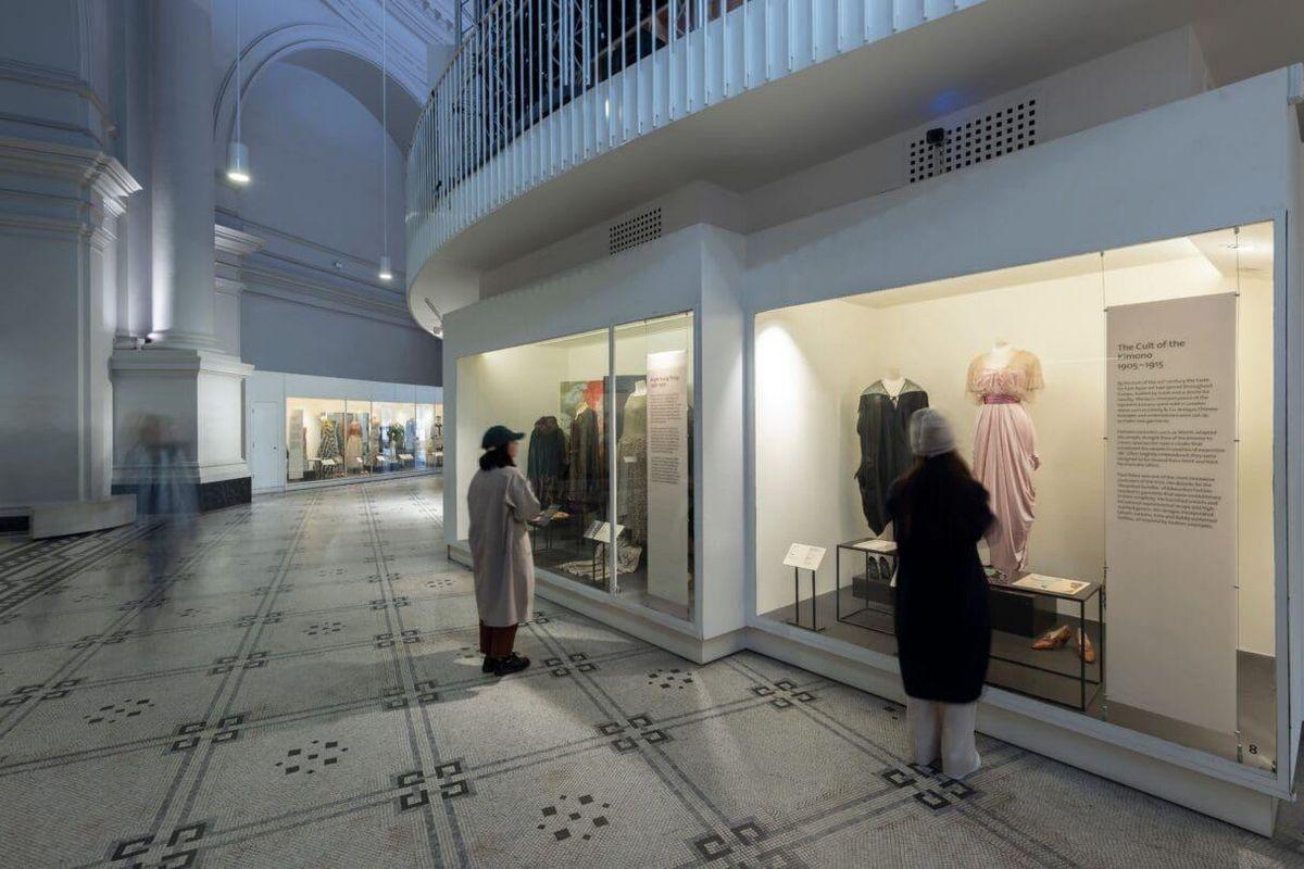 Visão lateral da galeria com paredes brancas e escada visível, destacando o design moderno.