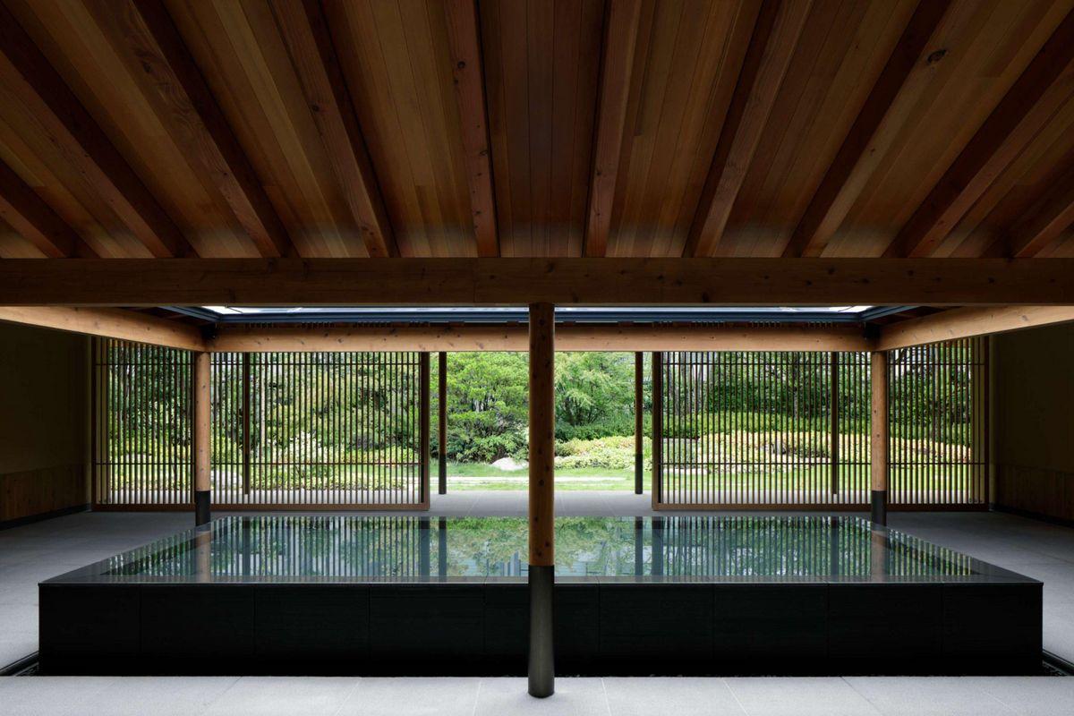 Área de chegada no hotel Roku Kyoto, destacando um ambiente hospitaleiro com vegetação e arquitetura moderna.