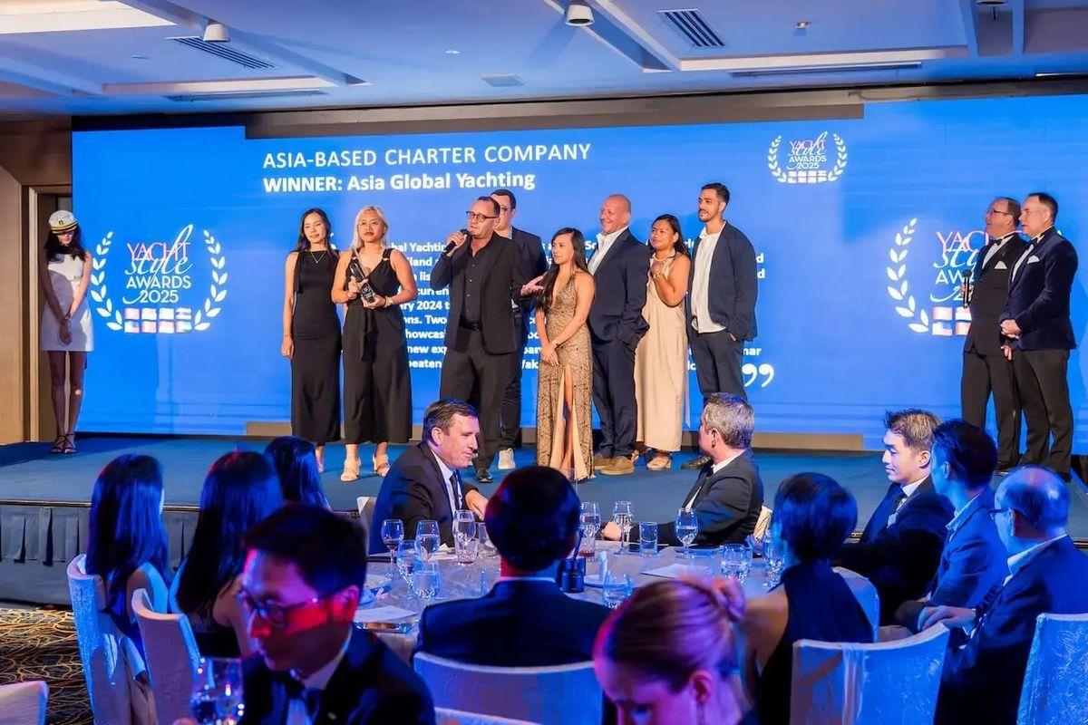 Indivíduos em trajes formais apresentando os troféus no Yacht Style Awards 2025, com um telão ao fundo mostrando informações sobre os vencedores.
