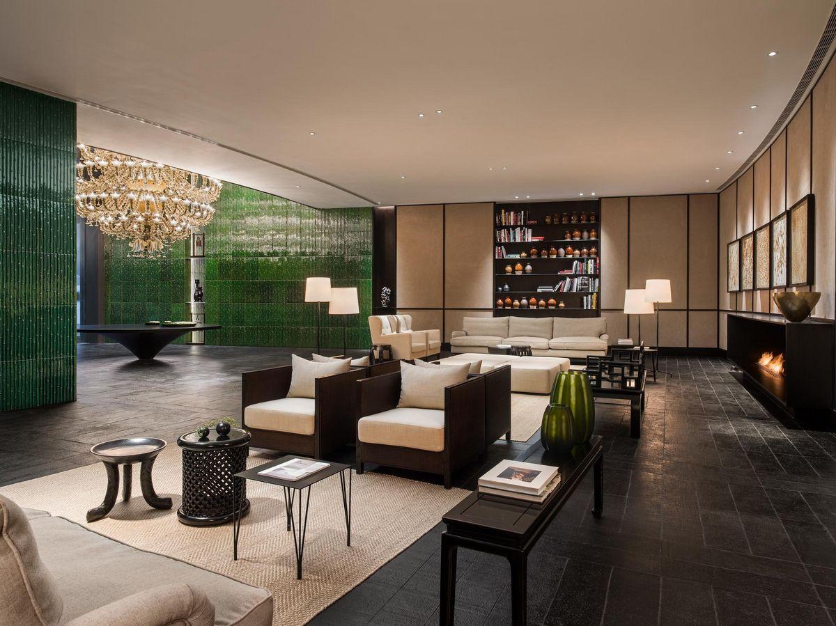 Lobby contemporâneo com paredes verdes e decoração de madeira, oferecendo um ambiente acolhedor e elegante.