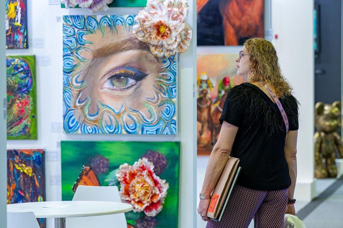 Um cenário com diversas obras de arte expostas e visitantes interagindo.