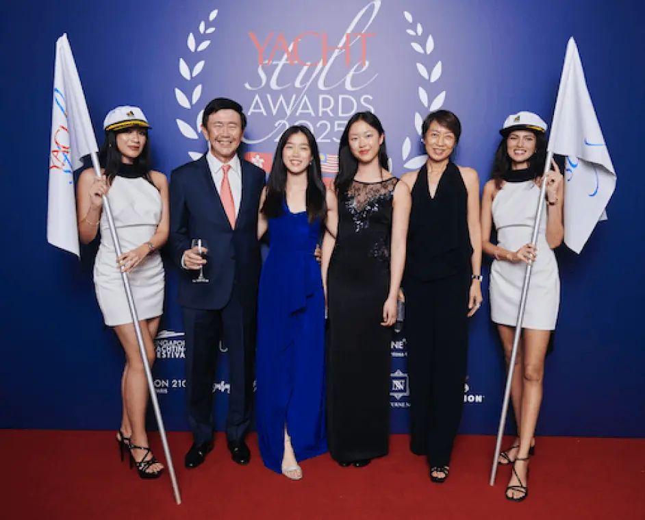 Um grupo de seis pessoas vestindo roupas formais em um ambiente temático de festa, com bandeiras e decoração, no Yacht Style Awards 2025.