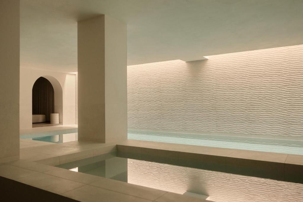 Uma piscina com água clara ao lado de uma parede decorada com um padrão ondulado.